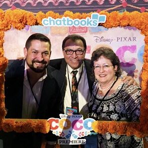 A group of people posing for a picture in front of a coco movie poster.